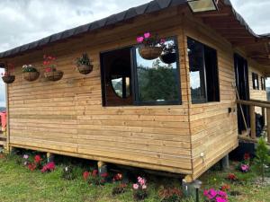 a wooden cabin with flower pots on the window at Cabaña del Sol in Medellín