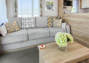 a living room with a gray couch and a table at Gorselands Caravan Park in Dorchester