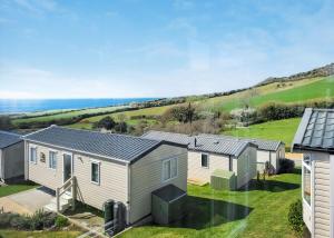 an image of a holiday home with the ocean in the background at Gorselands Caravan Park in Dorchester