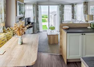 a kitchen and living room with a wooden table at Gorselands Caravan Park in Dorchester