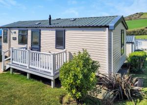 a holiday house with a deck and a view of the ocean at Gorselands Caravan Park in Dorchester