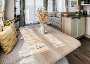 a living room with a wooden table and a couch at Gorselands Caravan Park in Dorchester +43 photos