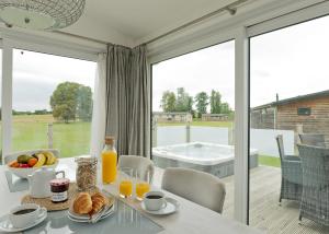 a dining room with a table and a view of a tub at Aspen Lodge Escape in Hengrave