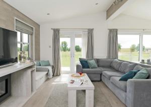 a living room with a couch and a tv at Aspen Lodge Escape in Hengrave