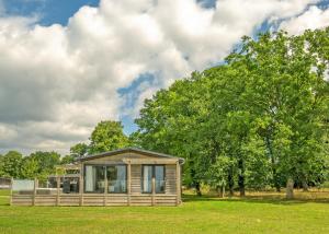 a small cabin in a field with a tree at Aspen Lodge Escape in Hengrave