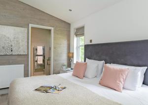 a bedroom with a large white bed with pink pillows at Aspen Lodge Escape in Hengrave +37 photos