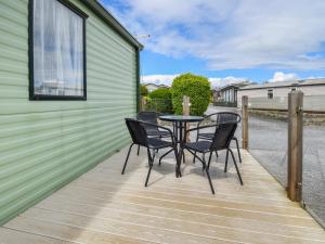 a patio with four chairs and a table on a deck at Fellside Lodge in Cockermouth