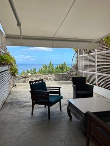 two chairs and a table on a patio with the ocean at La maison sur la plage in Saint-Pierre
