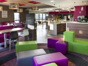 ein Restaurant mit farbenfrohen Stühlen und Tischen und einer Bar in der Unterkunft ibis Styles Castres in Castres