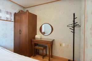 a bedroom with a dressing table and a mirror at Four Season Pension in Seogwipo
