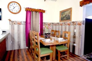 a dining room table with chairs and a clock on the wall at villa los recuerdos in Jarabacoa