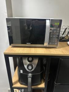 a microwave sitting on top of a shelf at D Castro Art House in Montes Claros