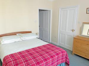 a bedroom with a bed with a plaid blanket at Belgravia Cottage in Skipton