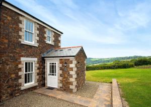 a brick house with a white door and a grass field at Green Acres Cottages in Par
