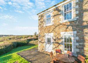 a stone house with a table and chairs outside at Green Acres Cottages in Par