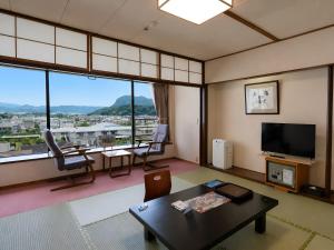 a living room with a table and a large window at Hotel Sunvalley Fujimi in Izunokuni