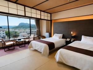 a hotel room with two beds and a large window at Hotel Sunvalley Fujimi in Izunokuni