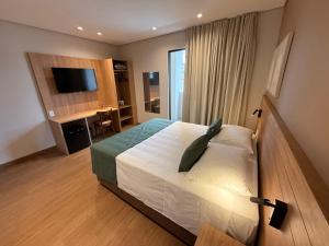 a bedroom with a bed and a desk and a television at POUSADA MILÊNIO LTDA in Ponte Nova