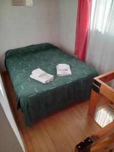 a small bed with green sheets and towels on it at Refugio del Viento in Gobernador Gregores