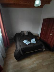a bedroom with a black bed with two towels on it at Refugio del Viento in Gobernador Gregores