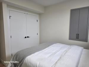 a white bedroom with a bed and two white cabinets at Executive Luxury Suite Unit B in Regina