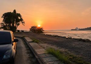 a car parked on a beach at sunset at Osvy Palm Homestay in Penampang