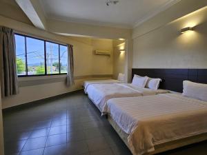 a hotel room with two beds and a window at Hotel Sitiawan in Sitiawan