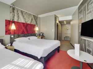 a hotel room with two beds and a flat screen tv at ibis Saint Germain en Laye Centre in Saint-Germain-en-Laye +104 photos