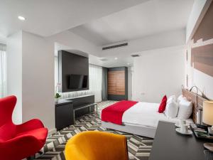 a hotel room with a bed and a red chair at Mercure Bucharest Unirii in Bucharest