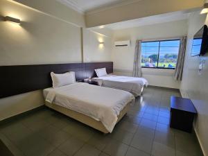 a hotel room with two beds and a window at Hotel Sitiawan in Sitiawan
