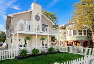 a white fence in front of a house at Coastal Chateau Cottages in Ocean City
