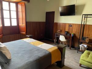 a bedroom with a bed and a desk and a television at Hotel Muchá in Quetzaltenango +41 photos