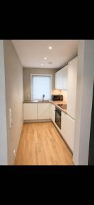 a kitchen with white cabinets and a wooden floor at Rekkehus i Sandnes in Stavanger