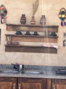 a kitchen with wooden shelves above a sink at Siwa Spot - Authentic Siwan Room with Private Patio in Siwa