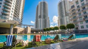a swimming pool with lawn chairs and tall buildings at Modern Downtown Miami Studio with Skyline View in Miami