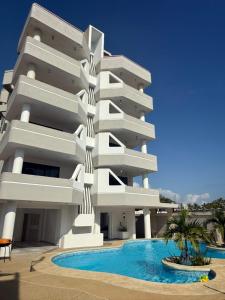 a white building with a swimming pool in front of it at Moderno apartamento 1 minuto de la playa in Chichiriviche