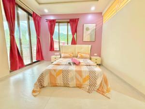 a bedroom with a bed with pink walls and windows at Sunset havan villa in Lonavala +9 photos