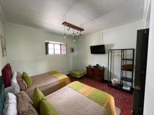 a room with two beds and a television in it at Hotel Muchá in Quetzaltenango