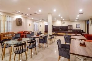 a restaurant with tables and chairs and a kitchen at Capital O Divira Inn in Dhanbād