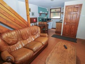 a living room with a leather couch and a table at Cabin No 3 - Salt and Fern Cabins in Port Talbot