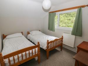 two beds in a room with a window at Cabin No 3 - Salt and Fern Cabins in Port Talbot