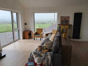 a living room with a couch and large windows at Tigh Droum in Rosscarbery
