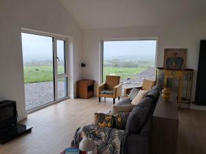 a living room with a couch and large windows at Tigh Droum in Rosscarbery