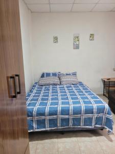 a bed in a white room with a blue blanket at Hostal viroleño in Zacatecoluca
