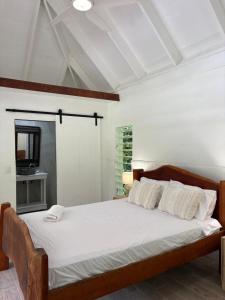 a bedroom with a large bed with white sheets at Coconut Beach House & Cottages in Cape Tribulation