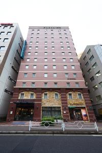 a tall building on a street with two tall buildings at Sotetsu Fresa Inn Nihombashi Kayabacho in Tokyo