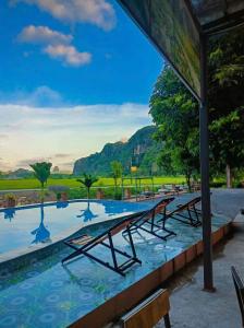 a row of benches in a pool with mountains in the background at Tam Cốc FAIRY WINGS Homestay in Vũ Lâm +11 photos