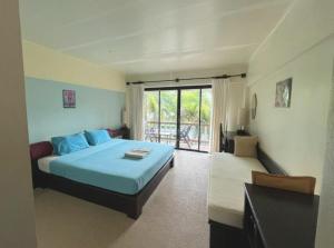 a bedroom with a blue bed and a balcony at Lanta Green Garden Hotel in Ko Lanta