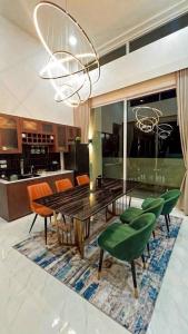 a dining room with a wooden table and green chairs at De Flourishing Hill Escape #2 in Ban Hup Kaphong