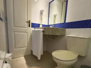 a bathroom with a white toilet and a blue tile wall at Center Verdes Pássaros Loft in Porto Alegre